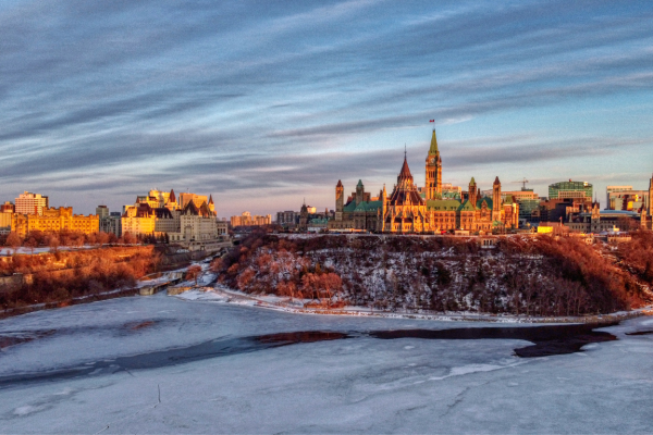 Foto de un lago cristalino en primer plano con una ciudad canadiense en el fondo, al atardecer.